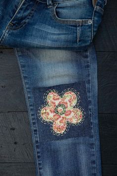 jeans with embroidered flowers on them are sitting next to each other