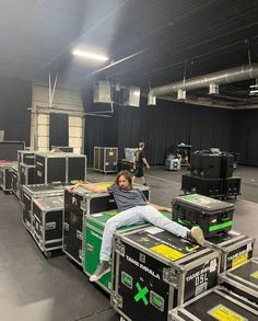 a man sitting on top of a green and black box in an empty room with other equipment