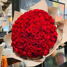 a large bouquet of red roses is wrapped in brown paper and sits on a table