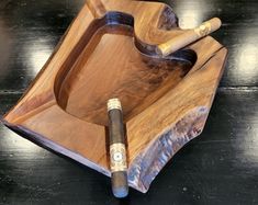 a wooden tray with two cigars and a lighter in it on a black table