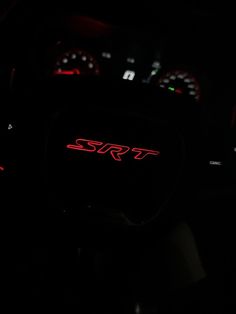 the interior of a car is lit up in the dark with red letters on it