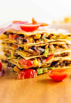 a stack of tortillas sitting on top of a wooden table next to sliced tomatoes