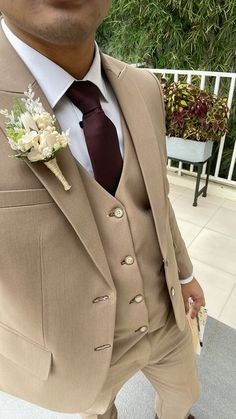 a man wearing a tan suit and tie with a flower in his lapel pocket