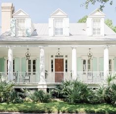 a white house with green shutters and palm trees in front of the porch area