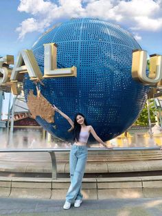 a woman standing in front of a giant blue globe