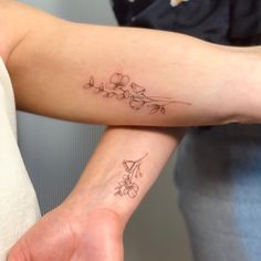 two people with matching tattoos on their arms, one is holding the other's arm