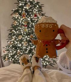 someone is holding a gingerbread man ornament in front of a christmas tree