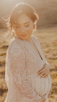 a pregnant woman standing in a field with the sun shining down on her head and shoulders