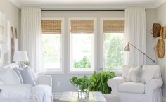 a living room filled with white furniture and lots of window coverings on the windowsill