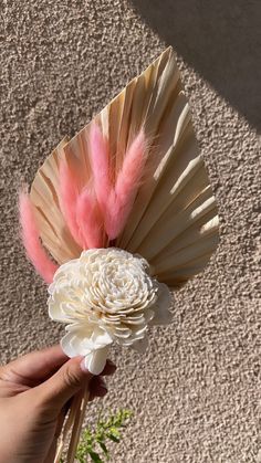 a hand holding a flower with feathers on it