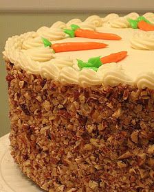 a cake with carrots and nuts on top is sitting on a white tablecloth