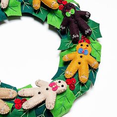 a christmas wreath made out of felt with teddy bears and holly leaves around it on a white background