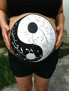 a pregnant woman holding a painted yin - yang ball