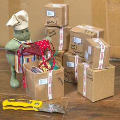 several boxes and scissors are stacked on top of each other in front of a stuffed animal wearing a chef's hat