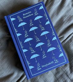 a blue book sitting on top of a bed with an umbrella cover over it's head