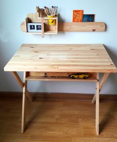 a wooden desk sitting on top of a hard wood floor next to a white wall