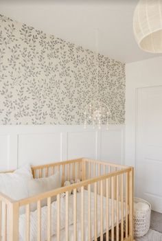 a baby crib in front of a white door and wall with flowers on it