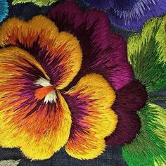 a close up view of a flower with multicolored petals on black fabric background