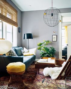 a living room filled with furniture and a lamp hanging from the ceiling next to a window