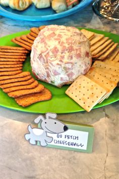 cheese ball and crackers on a green plate with a dog magnet next to it