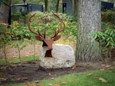 a statue of a deer with antlers on it's head near a tree