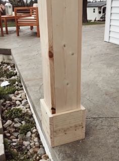 a tall wooden pole sitting on top of a cement floor next to a garden area