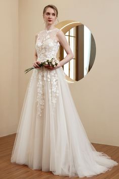 a woman standing in front of a mirror wearing a wedding dress with flowers on it