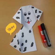 an origami dalmatian dog is on the table next to some markers