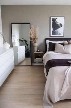 a bed room with a neatly made bed and two pictures on the wall above it