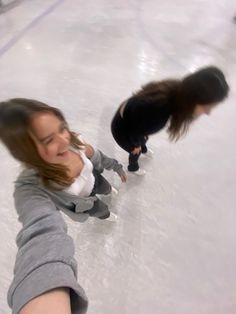 two girls are skating on an ice rink