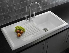 a white sink sitting under a faucet next to a counter top with fruit on it