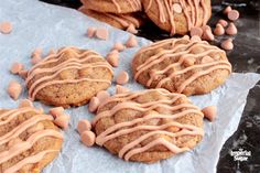 cookies with frosting and chocolate chips are on a piece of wax paper next to other cookies