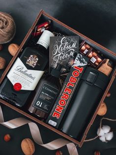 an open box containing liquor, nuts and chocolates on a black table with white ribbon