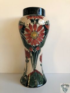 a vase with flowers painted on it sitting on a table