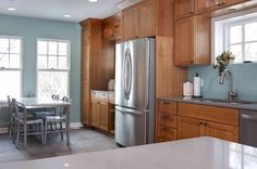 a stainless steel refrigerator in a kitchen with wooden cabinets and counter tops, along with an ice dispenser