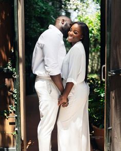 a man and woman are standing in an open doorway holding each other's hands