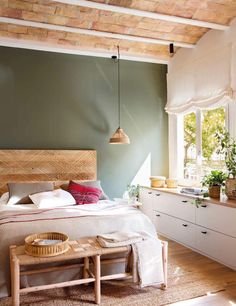 a bed room with a neatly made bed next to a window and a wooden bench