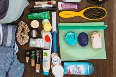 the contents of a purse laid out on top of a wooden table, including toothbrushes and other items