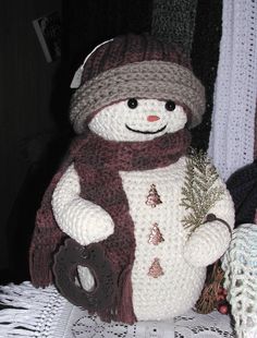 a crocheted snowman with a hat, scarf and mitten on top of a table