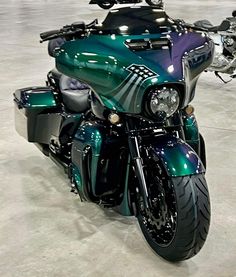 a green motorcycle parked in a garage next to other motorcycles