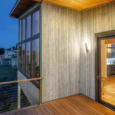 a wooden deck with glass doors leading to an outside kitchen