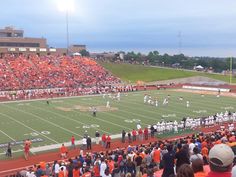 an orange and white football game is being played on a field with many people watching