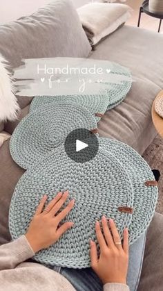 a woman sitting on top of a couch with her hands on the rug that is knitted