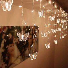 some lights are hanging from the ceiling in front of a photo and butterflies on it