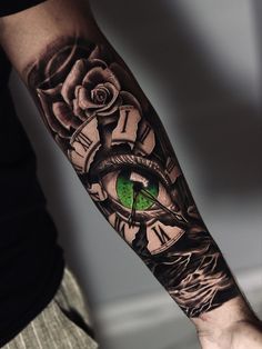 a man's arm with a clock and green eye tattoo on the left forearm