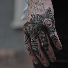 a person's hand with a sun and moon tattoo on it, while the other hand is black