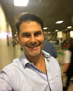 a smiling man in a blue shirt is taking a selfie