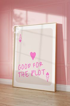 a pink room with a white framed poster on the wall that says, good for the plot