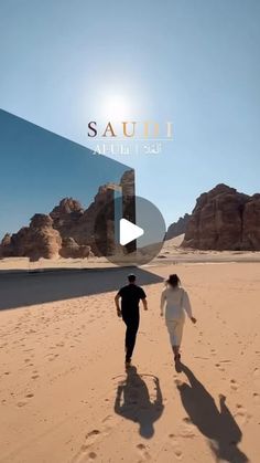 two people are walking in the sand near some mountains and desert rocks, with text saudi at the top