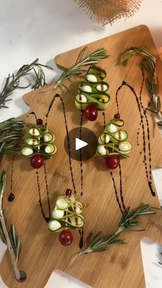 a cutting board topped with cucumbers and cherries on top of a table